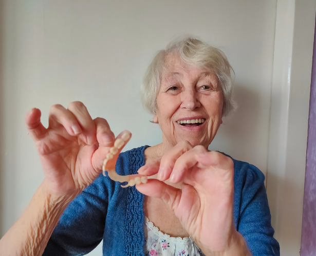 Happy senior woman holding a partial denture