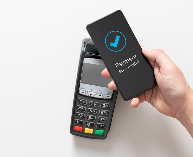Hand holding a smartphone over a card terminal with a payment successful message