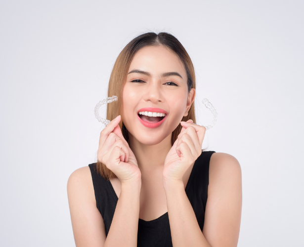Smiling woman holding two clear Invisalign trays