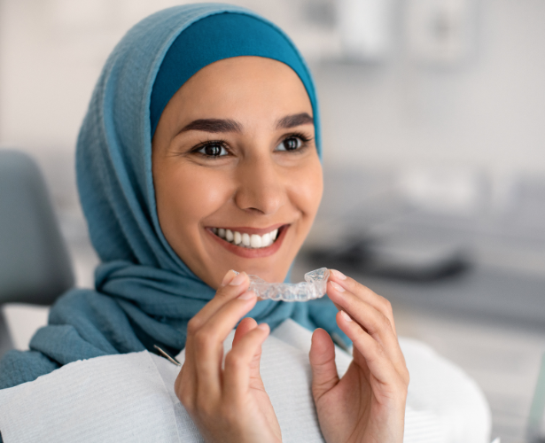 Woman in a dental chair holding a clear Invisalign tray