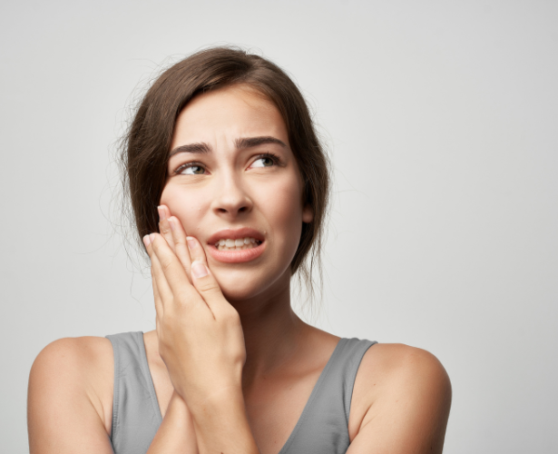 Woman holding her cheek with severe tooth pain before root canal